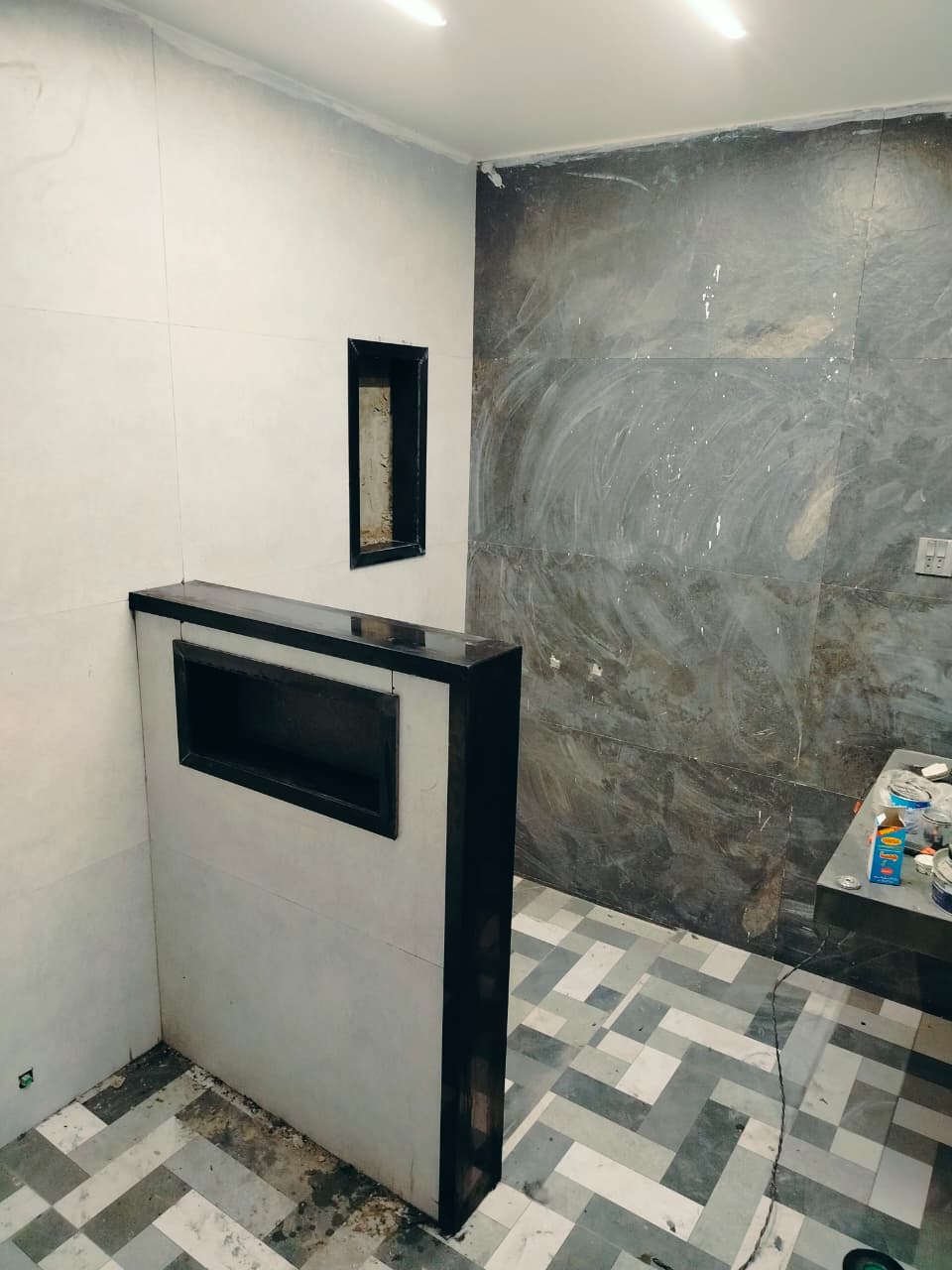 Bathroom during fit-out, with a niche partition and herringbone floor