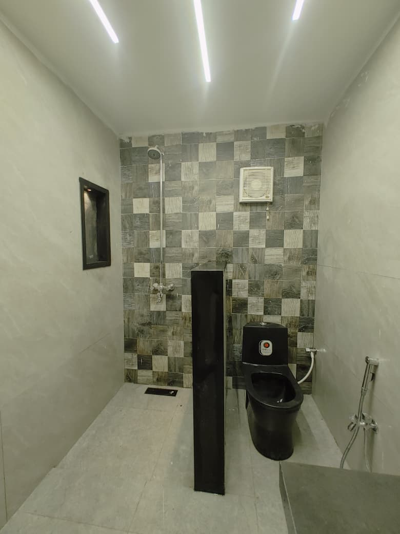 Shower area with patterned wall tiles, a black WC and a lit niche
