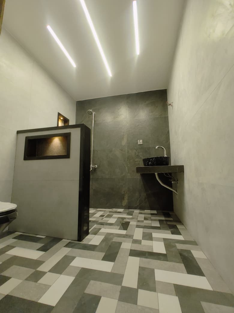 Bathroom with herringbone floor tiles, a slate-effect shower wall and a lit niche