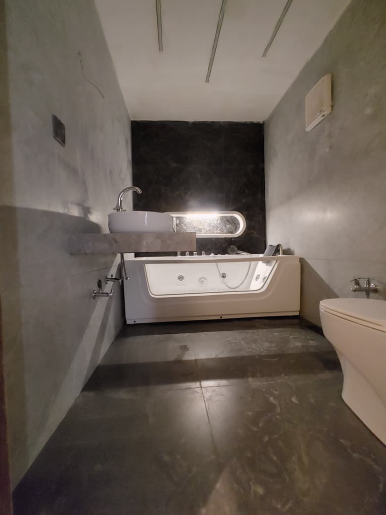 Whirlpool bath with an illuminated feature mirror on a dark marble wall