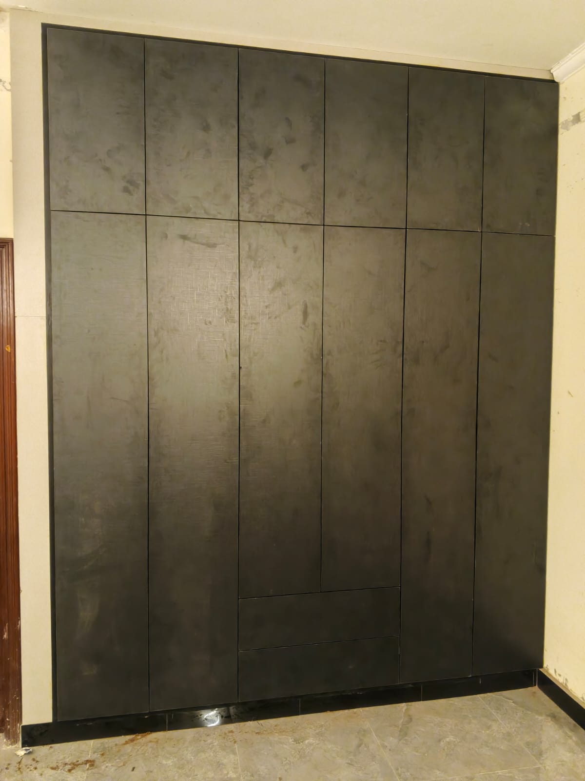 Handle-less floor-to-ceiling wardrobe in a dark textured finish