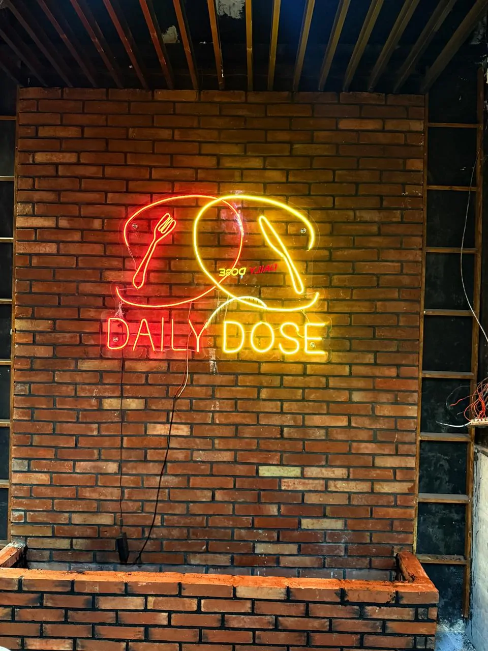 Daily Dose neon sign mounted on the exposed brick wall during the fit-out