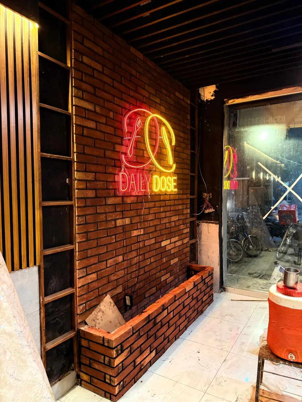 Brick-clad entrance wall with the Daily Dose neon sign, before finishing