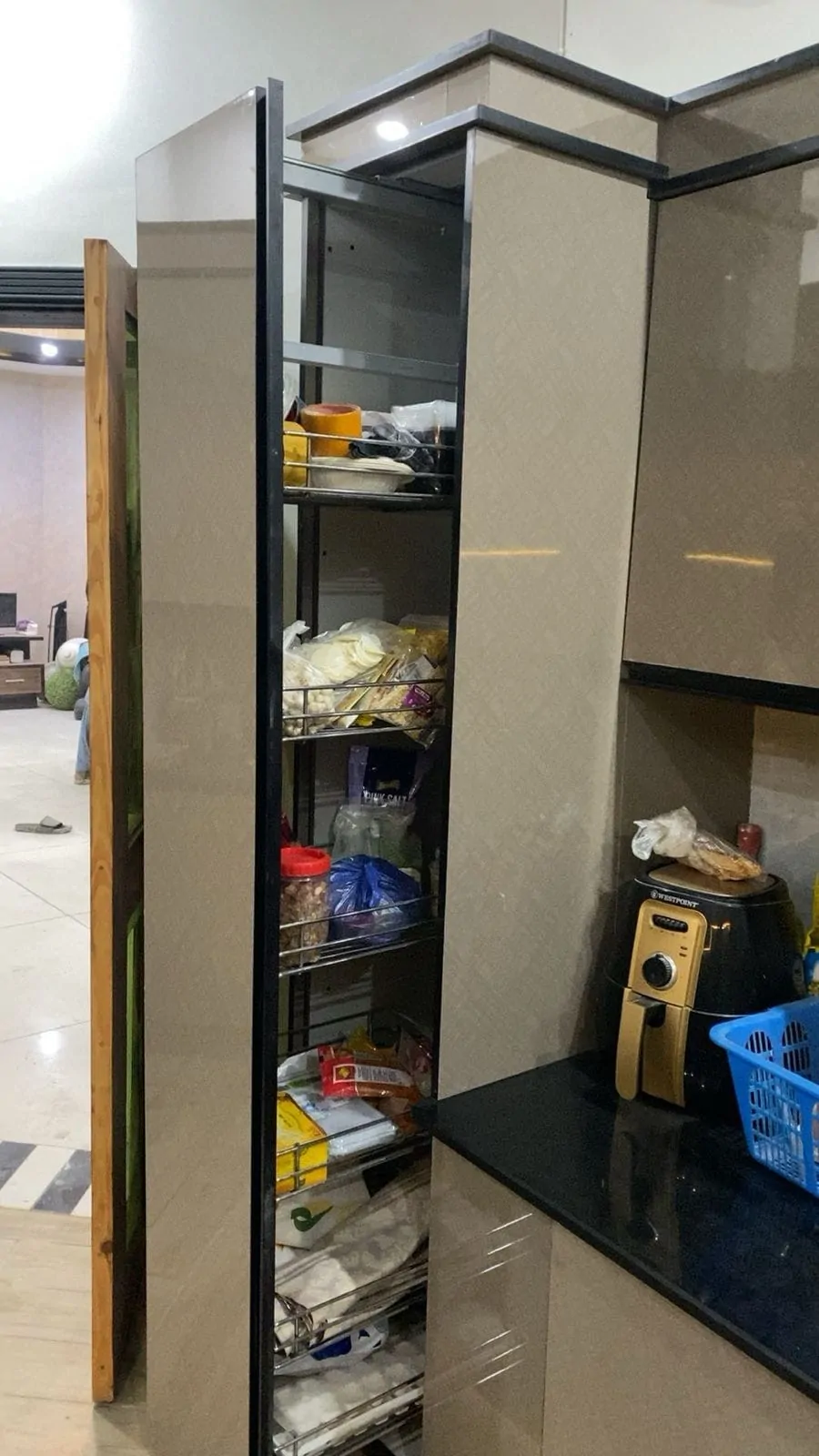 Tall kitchen unit with a pull-out pantry rack in a high-gloss finish
