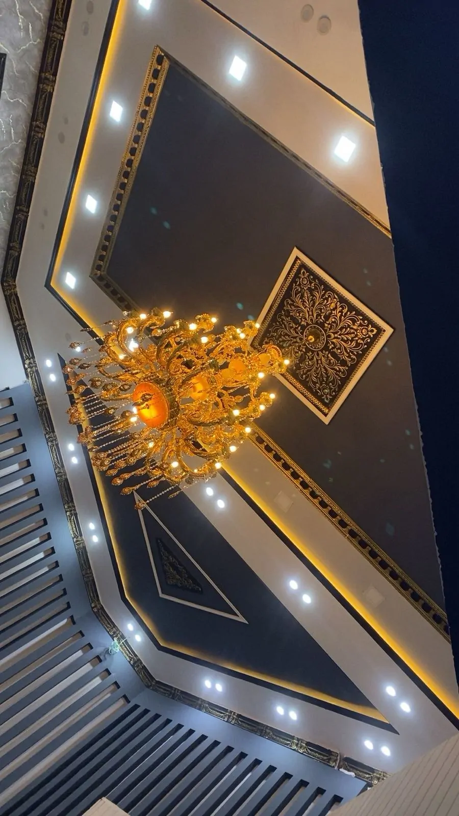 Tiered ceiling with gold cornice, recessed lights and a crystal chandelier
