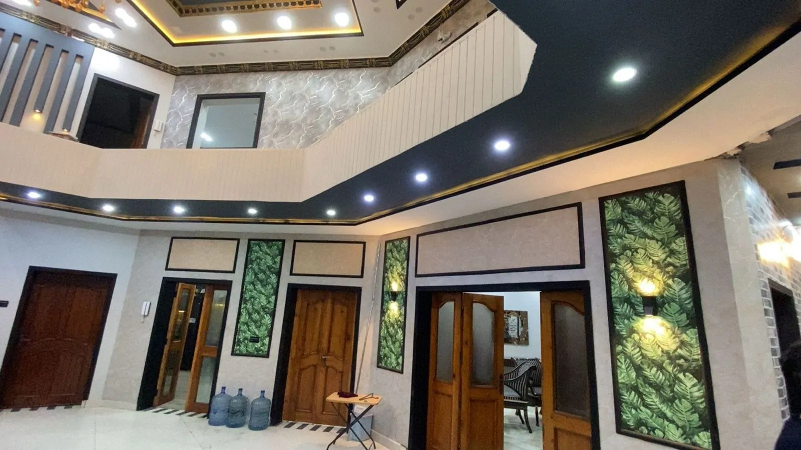 Entrance hall with leaf-pattern wall panels, recessed lighting and the wraparound gallery