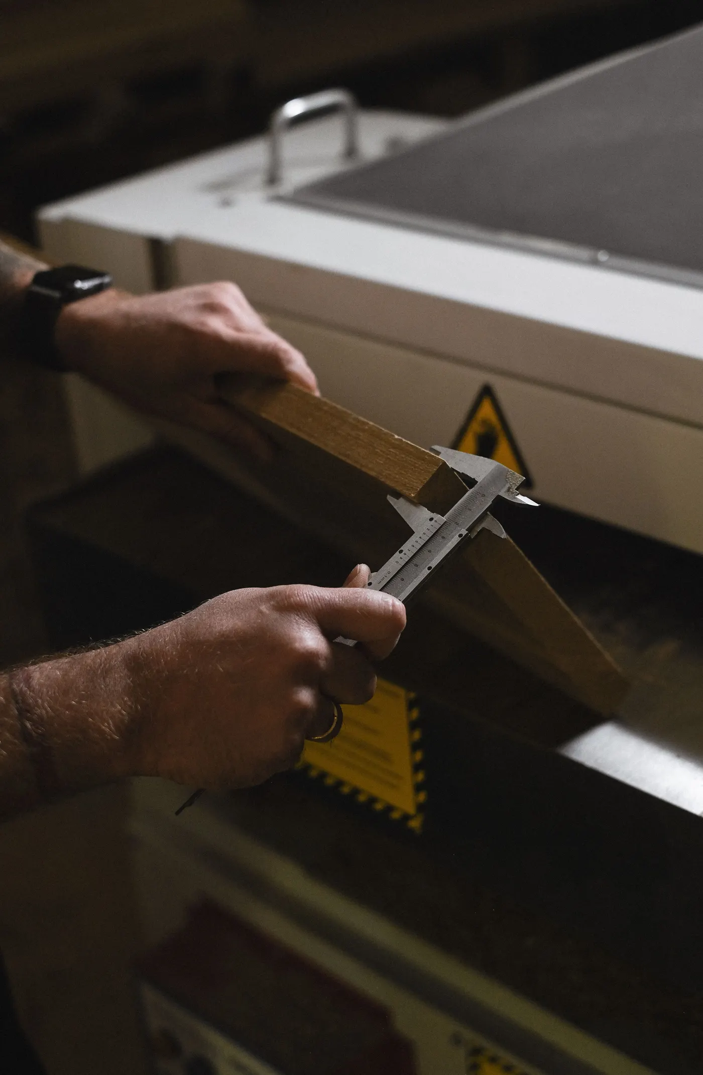 Craftsman measuring a timber plank with a vernier caliper