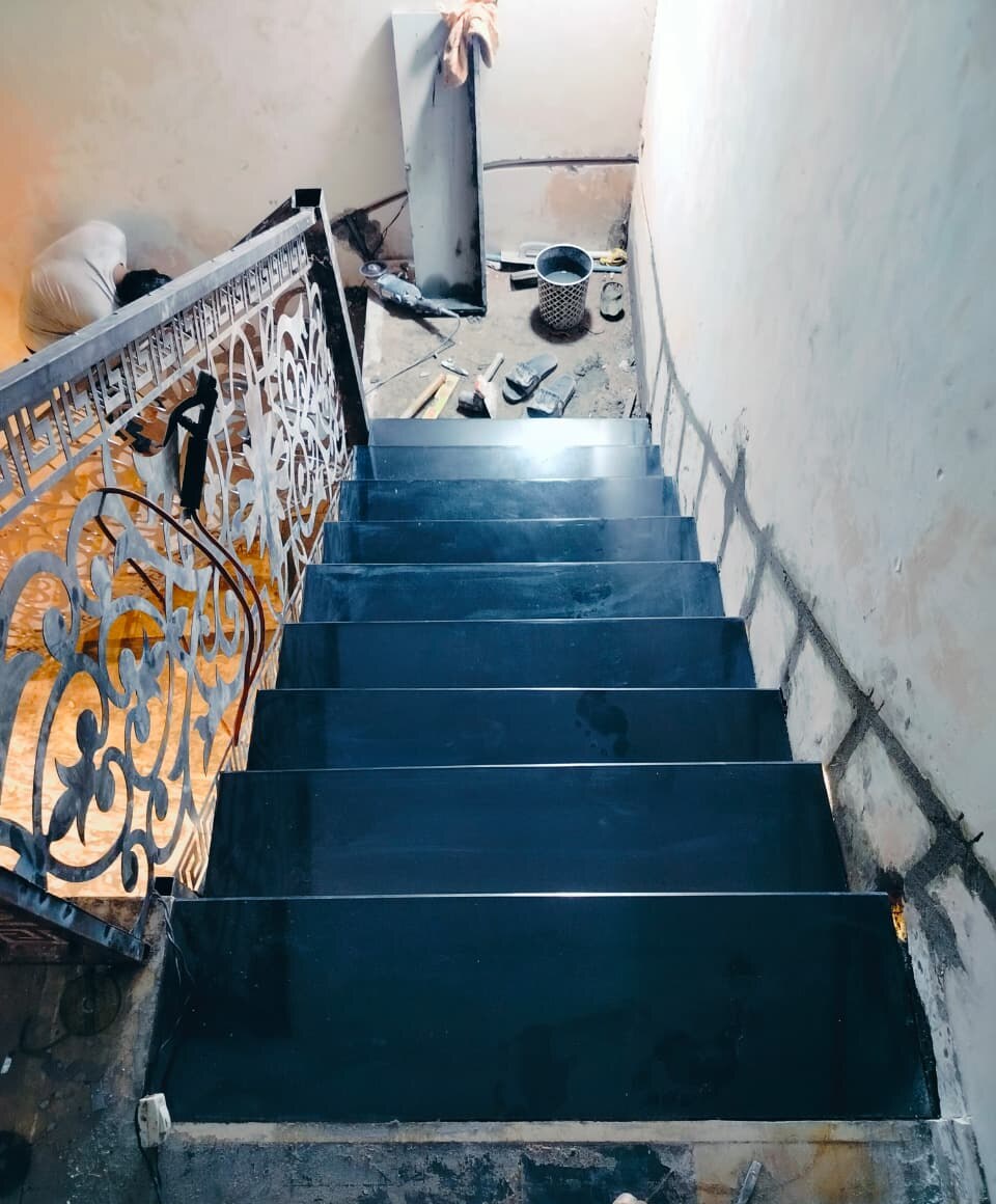 Staircase finished in black stone treads, seen from the landing