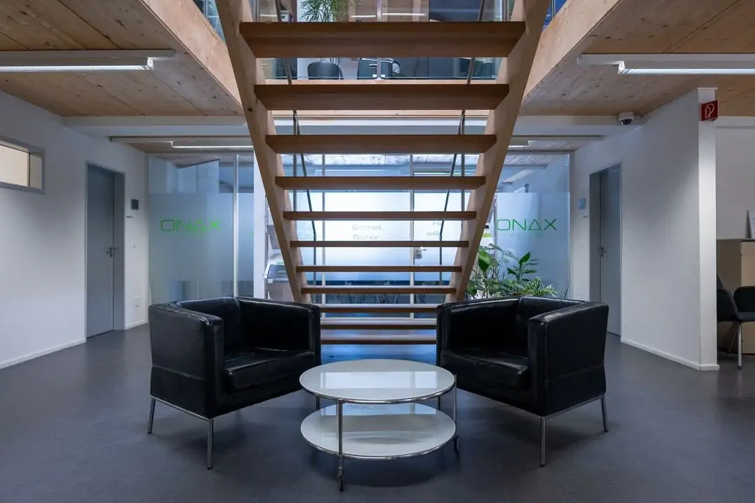 Commercial lounge with seating under a wooden staircase