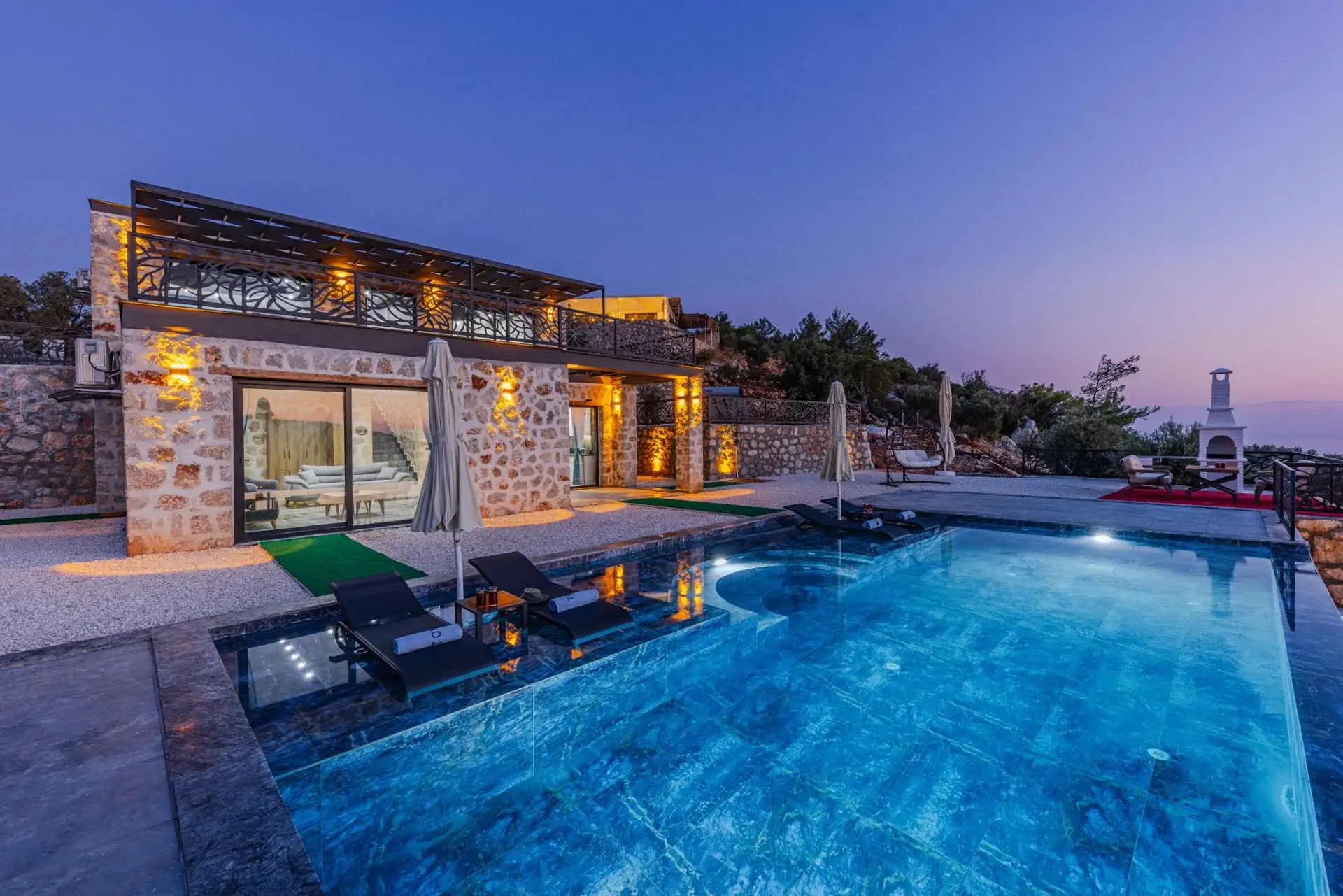 Contemporary stone villa with swimming pool at dusk